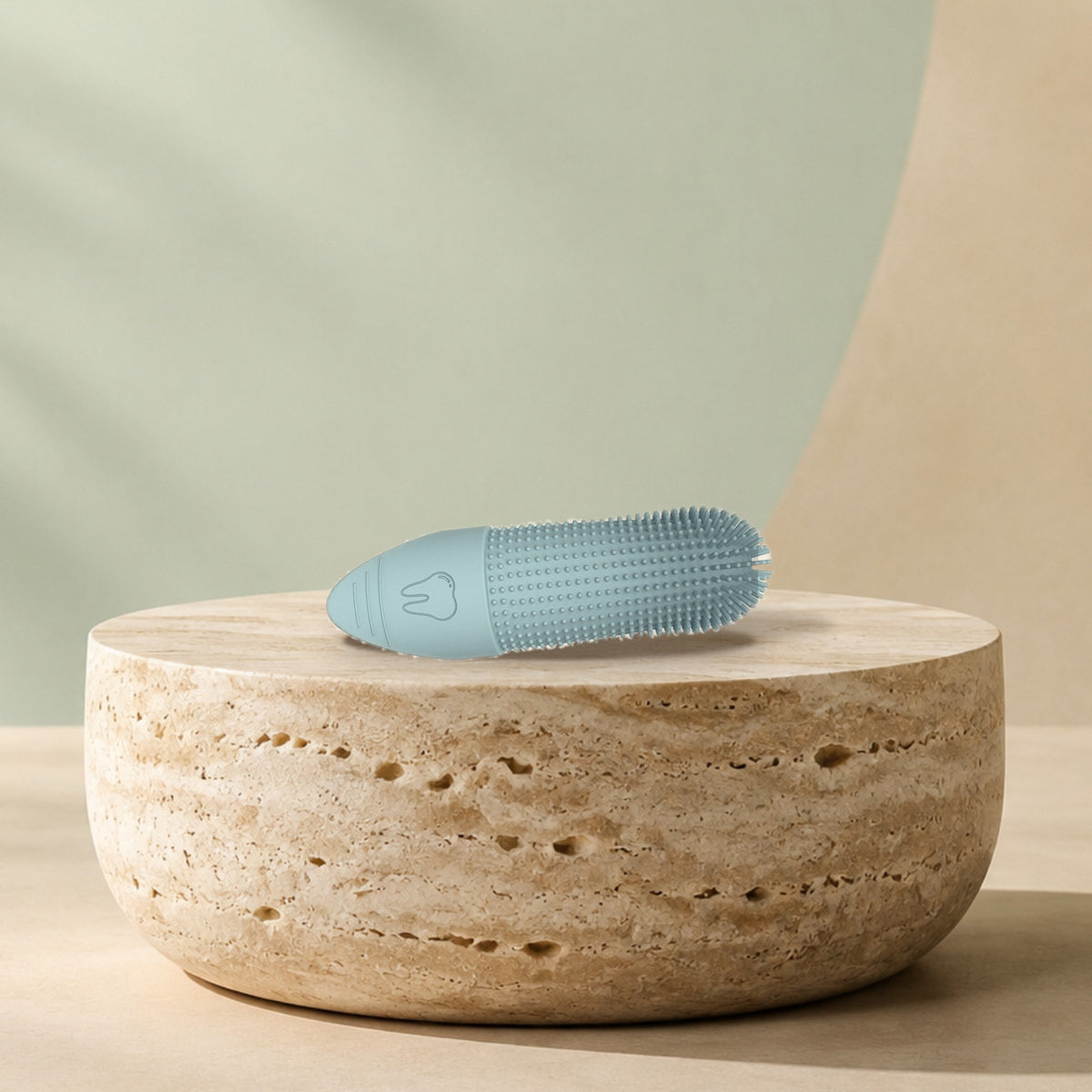 Doigtier brosse à dents en silicone posé sur un socle en travertin